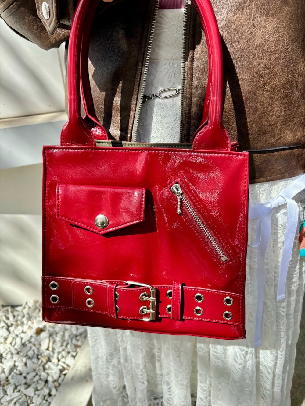 レッド系のハンドバッグ、レッド系のパンプス、ブラウン系のブルゾンを着用したレディースの夏コーディネートの7枚目の写真