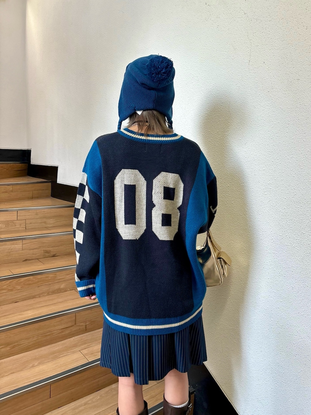 ブルー系のスカート、ゴールド系のハンドバッグ、ブラック系のニット/セーターを着用したレディースの夏コーディネートの5枚目の写真