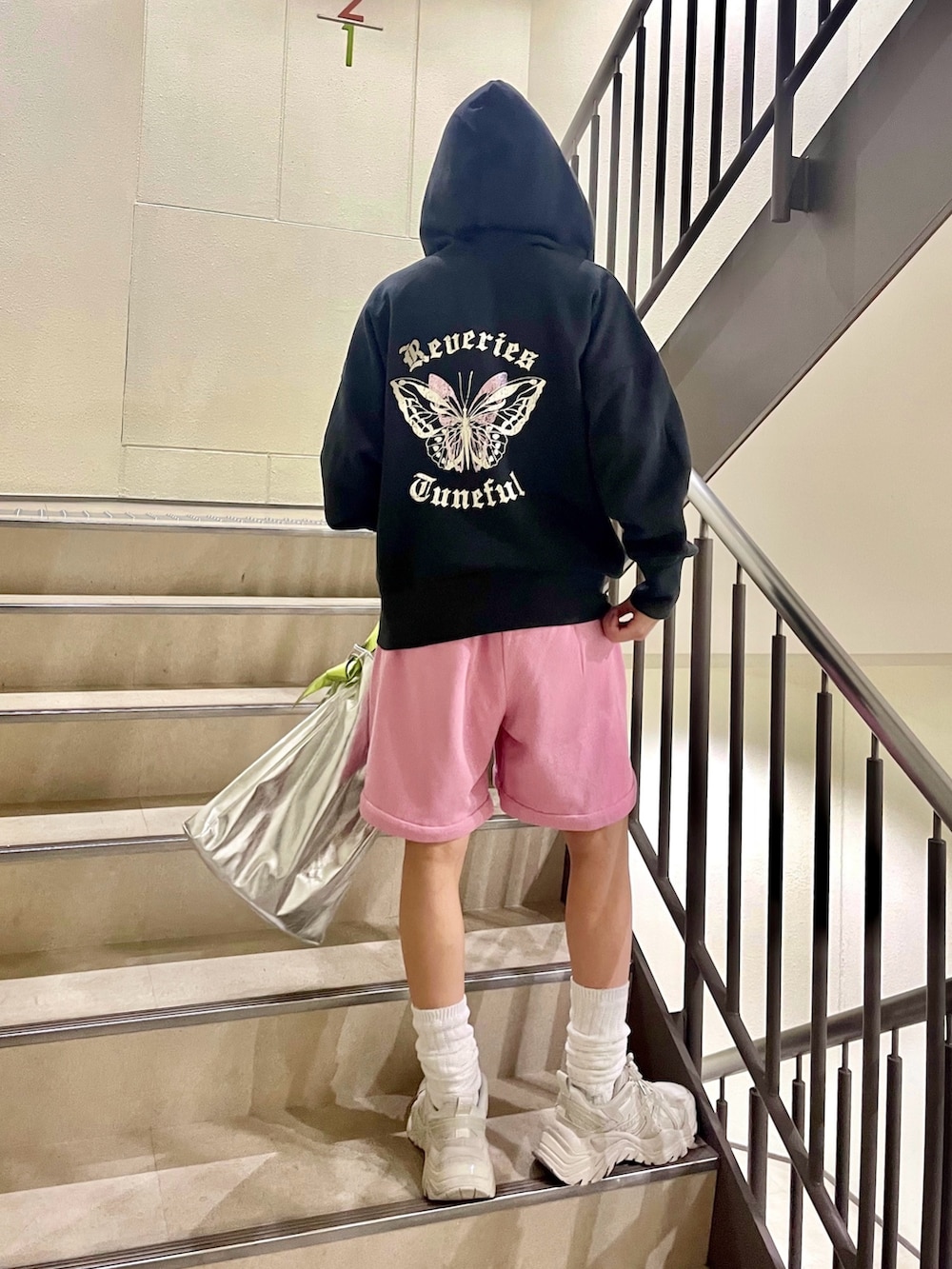 シルバー系のトートバッグ、ピンク系のスウェットパンツ、ブラック系のパーカーを着用したレディースの冬コーディネートの4枚目の写真