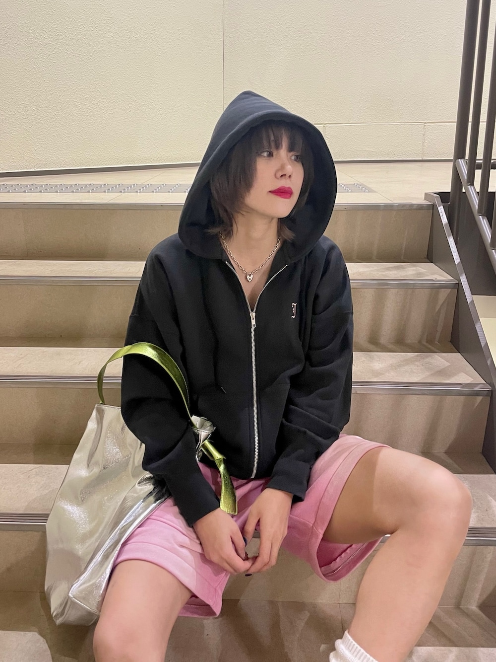 シルバー系のトートバッグ、ピンク系のスウェットパンツ、ブラック系のパーカーを着用したレディースの冬コーディネートの6枚目の写真