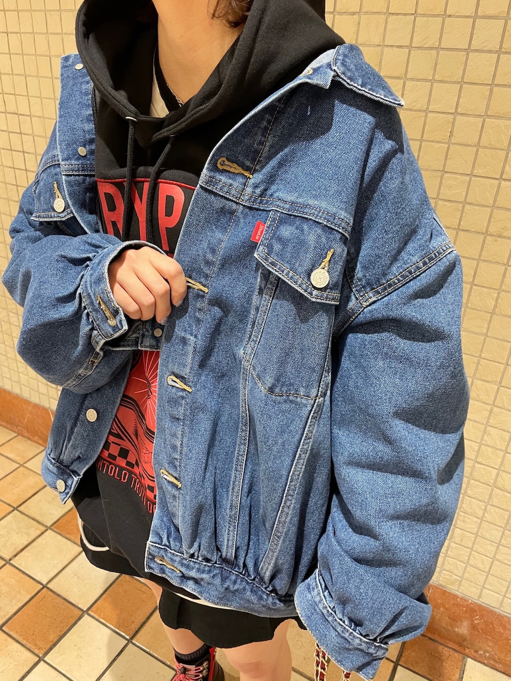 レッド系のトートバッグ、ブルー系のデニムジャケット、ブラック系のブーツを着用したレディースの冬コーディネートの8枚目の写真