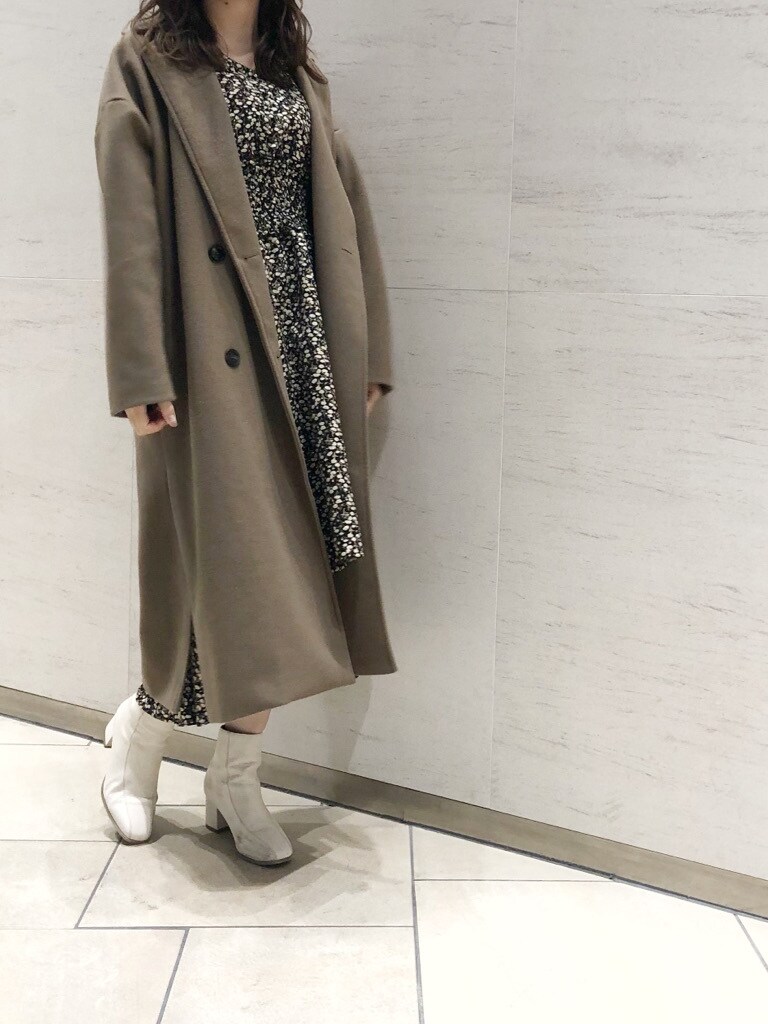 ホワイト系のブーツ、ベージュ系のその他アウター、ブラック系のワンピースを着用したレディースの冬コーディネートの2枚目の写真