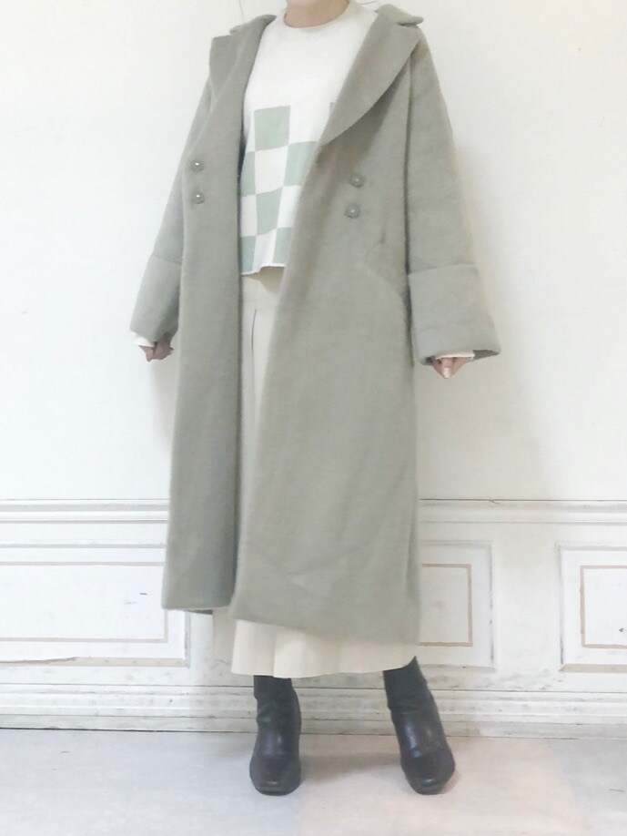 ベージュ系のスカート、グリーン系のニット/セーター、グリーン系のチェスターコートを着用したレディースの秋コーディネートの2枚目の写真