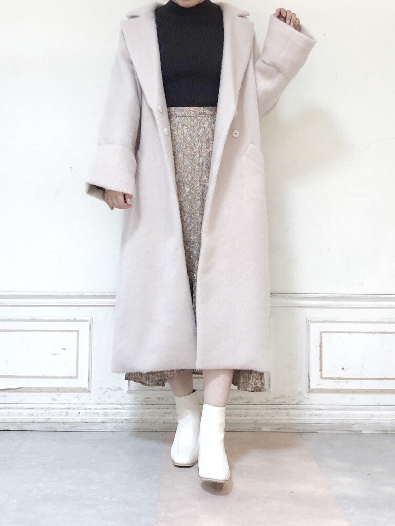 ホワイト系のブーツ、ホワイト系のチェスターコート、ホワイト系のスカートを着用したレディースの秋コーディネートの3枚目の写真