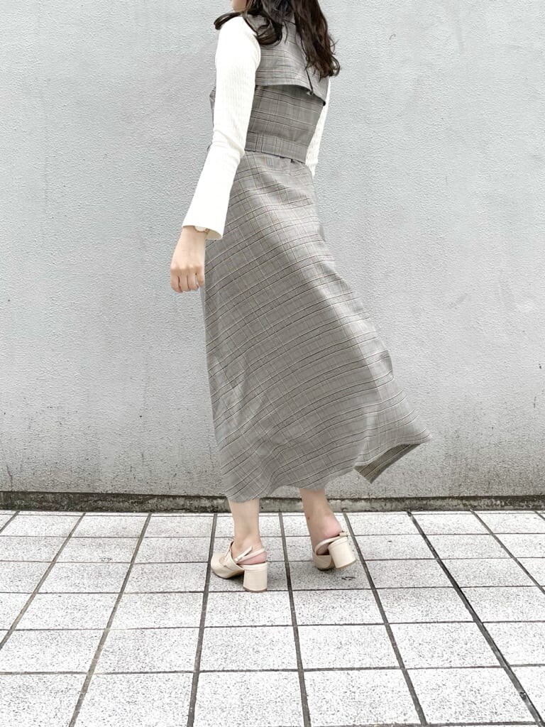 グレー系のワンピース、ホワイト系のニット/セーター、ホワイト系のパンプスを着用したレディースの秋コーディネートの3枚目の写真