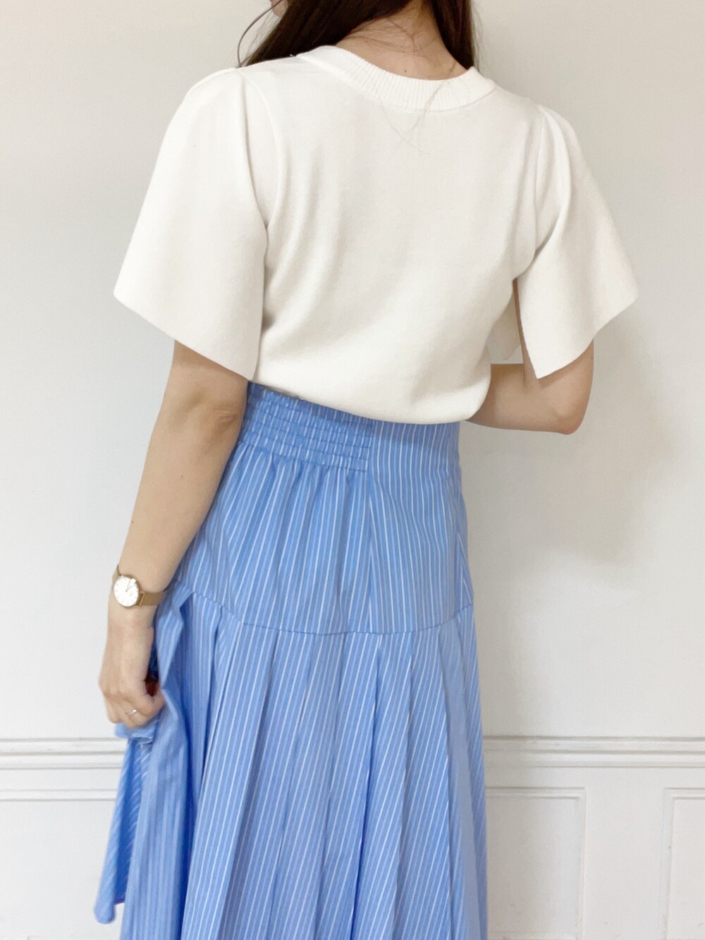 ホワイト系のニット/セーター、ブルー系のスカート、ホワイト系のパンプスを着用したレディースの春コーディネートの4枚目の写真