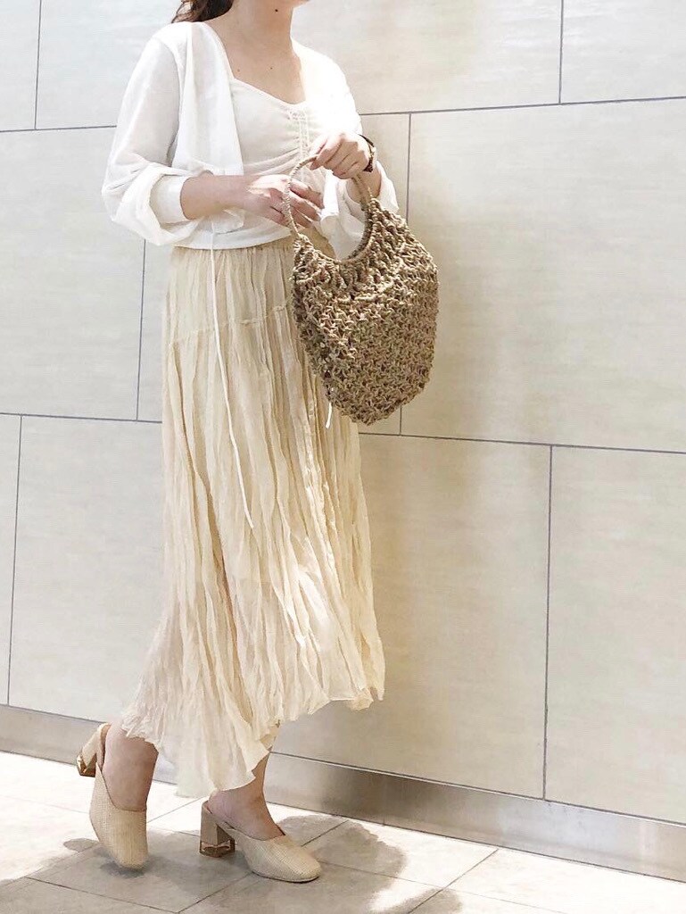 ホワイト系のスカート、ホワイト系のパンプス、ベージュ系のハンドバッグを着用したレディースの春コーディネートの2枚目の写真