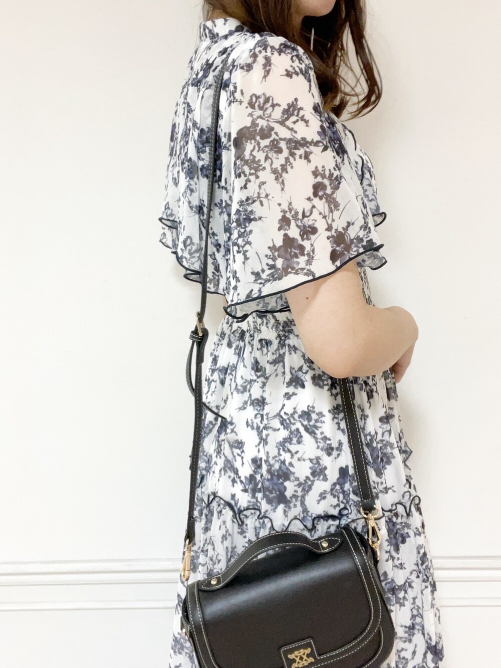 ホワイト系のワンピース、ブラック系のハンドバッグ、シルバー系のパンプスを着用したレディースの夏コーディネートの5枚目の写真