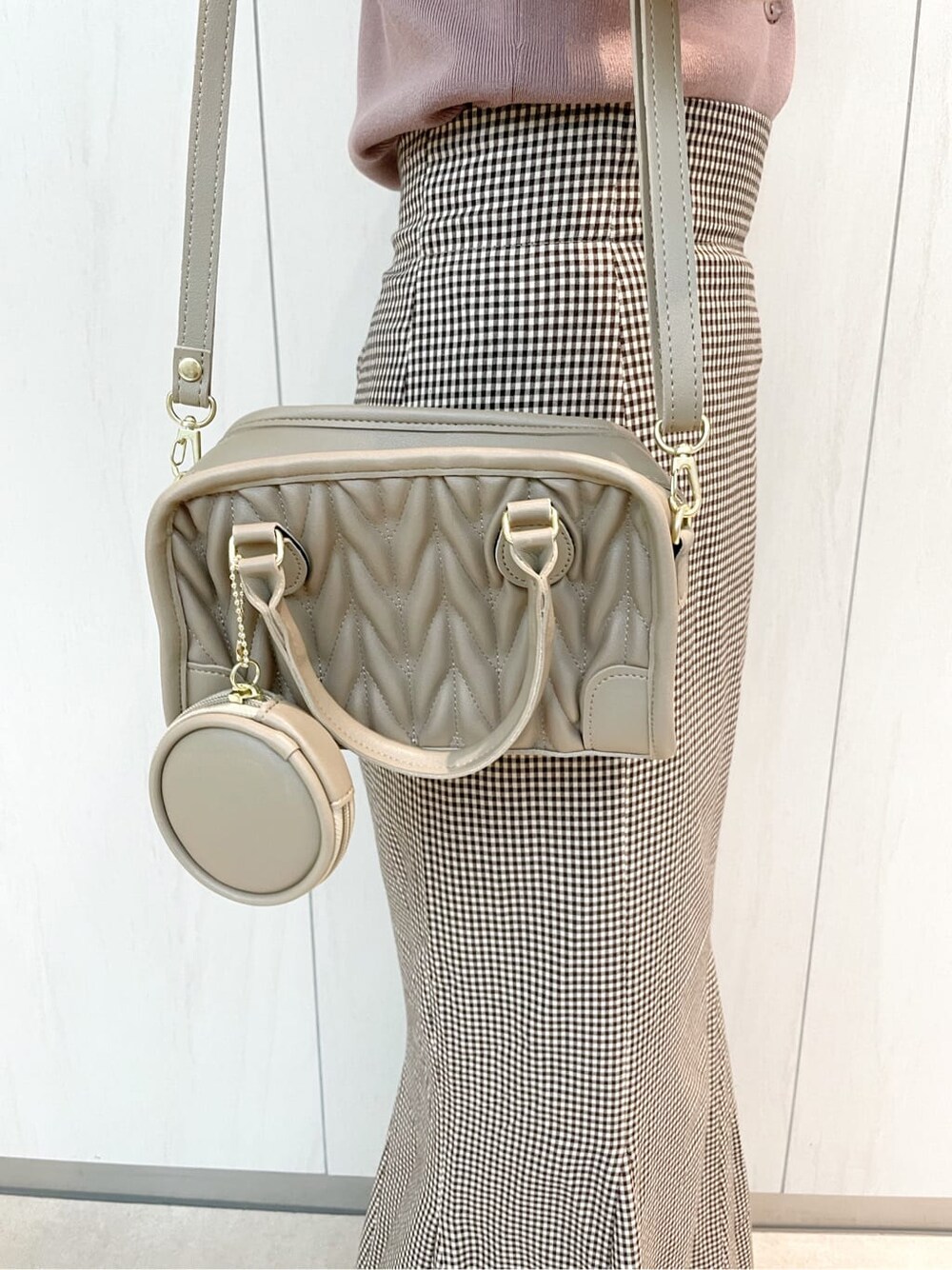 ブラウン系のスカート、ピンク系のニット/セーター、ベージュ系のハンドバッグを着用したレディースの秋コーディネートの7枚目の写真