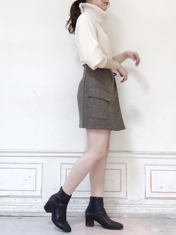 ブラウン系のスカート、ブラウン系のブーツ、ホワイト系のニット/セーターを着用したレディースの秋コーディネートの3枚目の写真