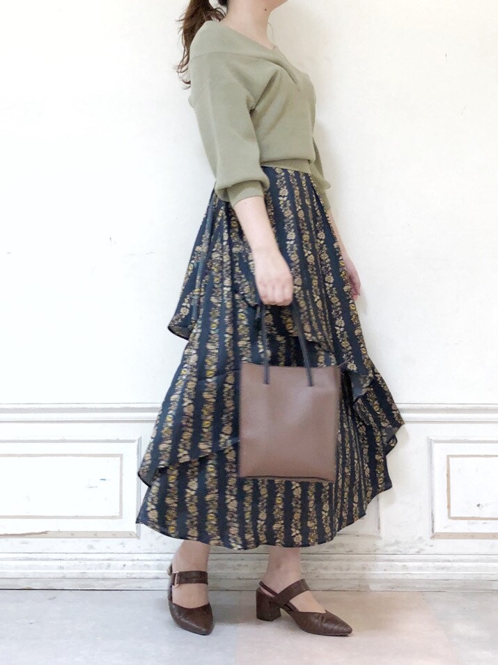 ブラック系のスカート、ブラウン系のハンドバッグ、グリーン系のニット/セーターを着用したレディースの秋コーディネートの3枚目の写真