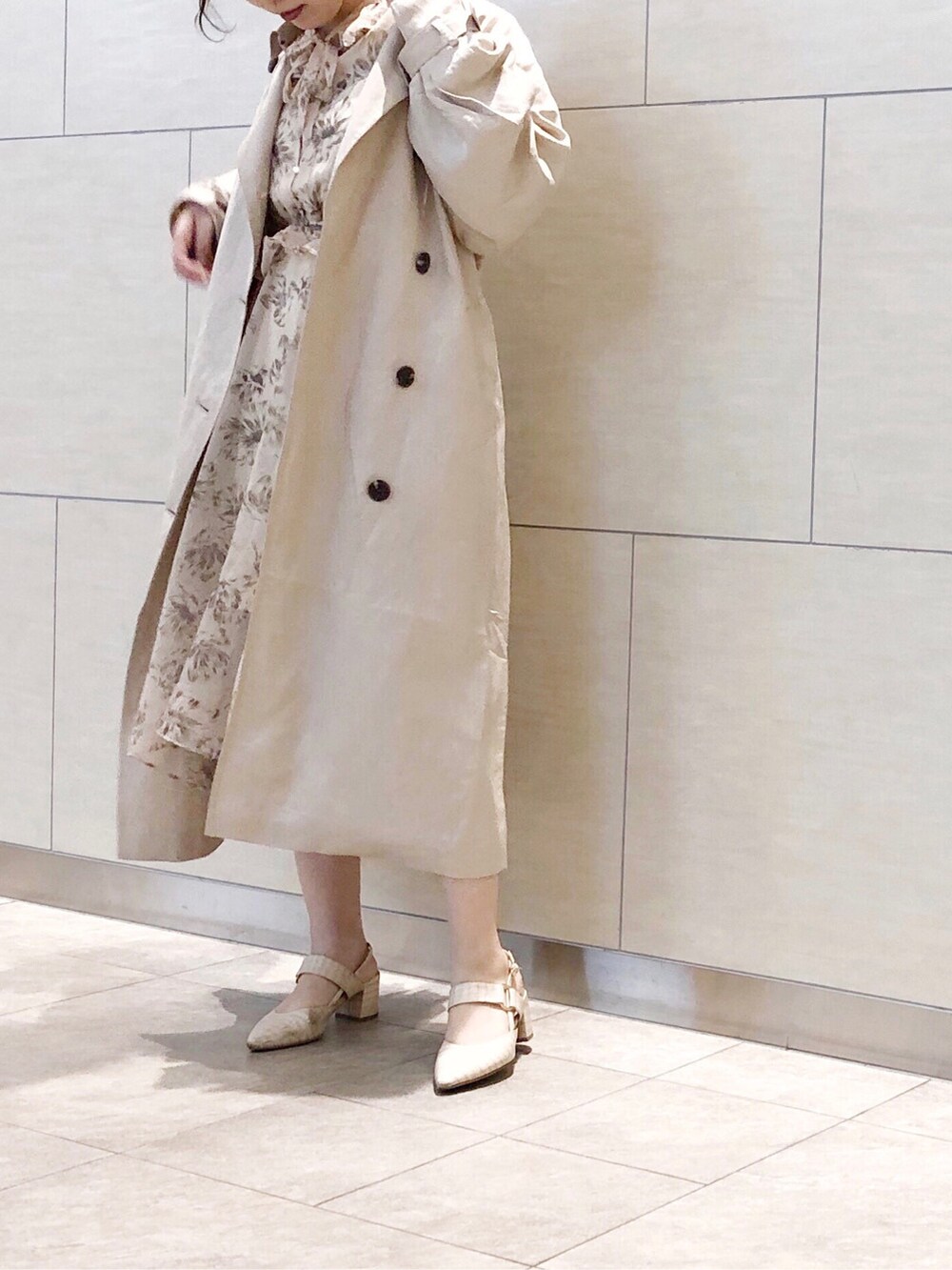ベージュ系のトレンチコート、ベージュ系のワンピース、ホワイト系のパンプスを着用したレディースの春コーディネートの3枚目の写真