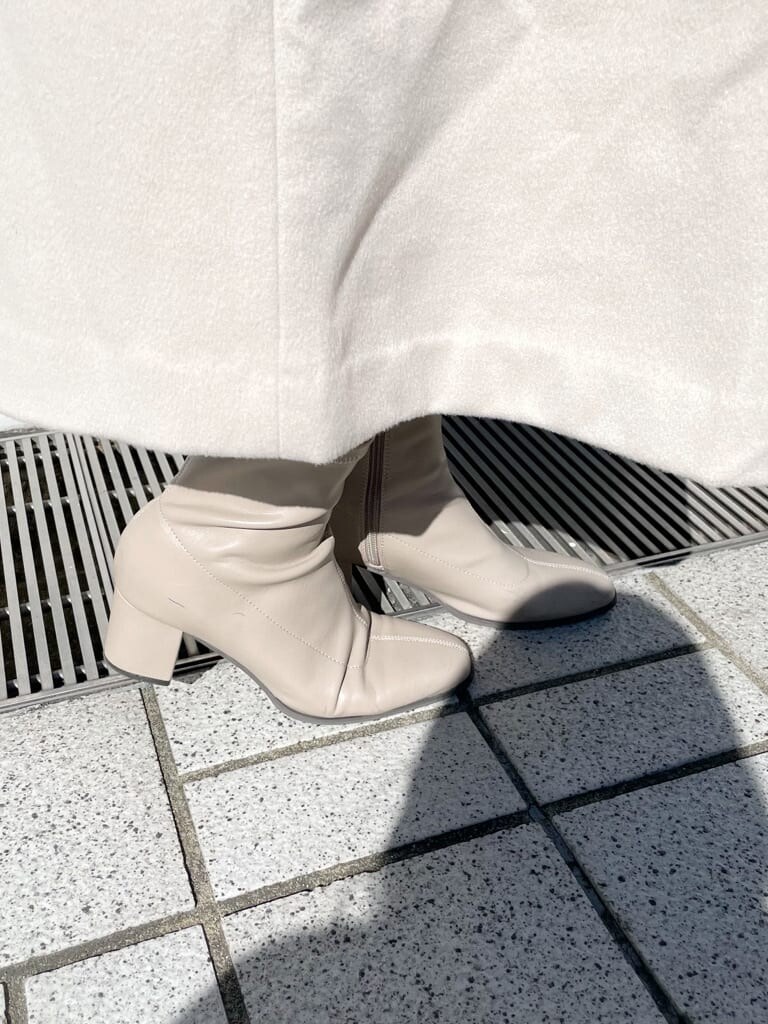 ホワイト系のその他アウター、ベージュ系のハンドバッグ、ベージュ系のブーツを着用したレディースの秋コーディネートの9枚目の写真