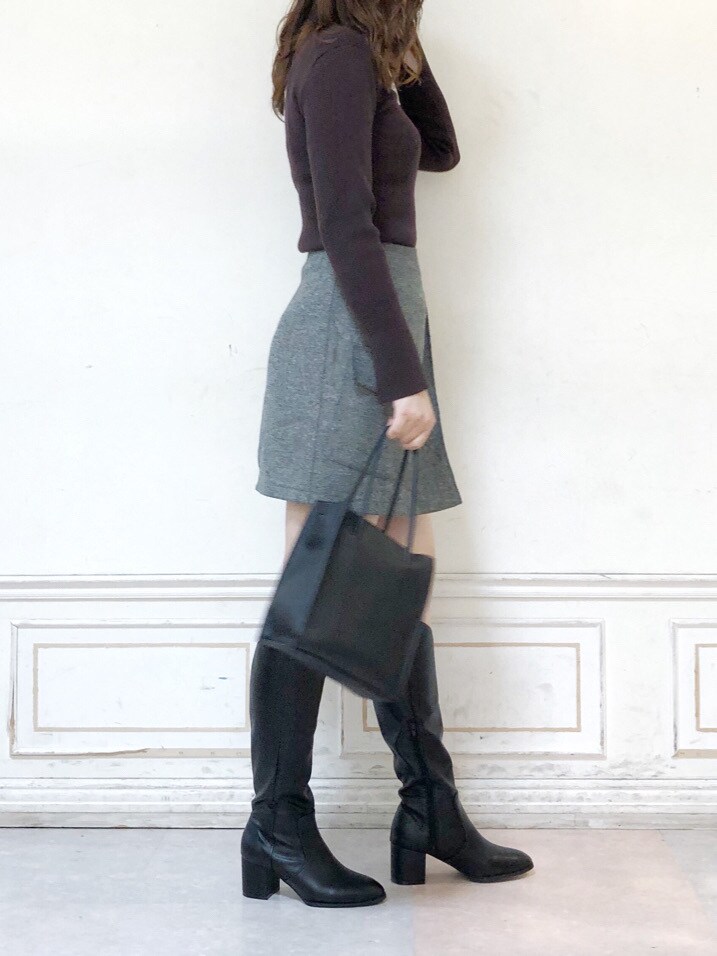 ブラウン系のニット/セーター、ブラック系のブーツ、ブラック系のハンドバッグを着用したレディースの秋コーディネートの2枚目の写真