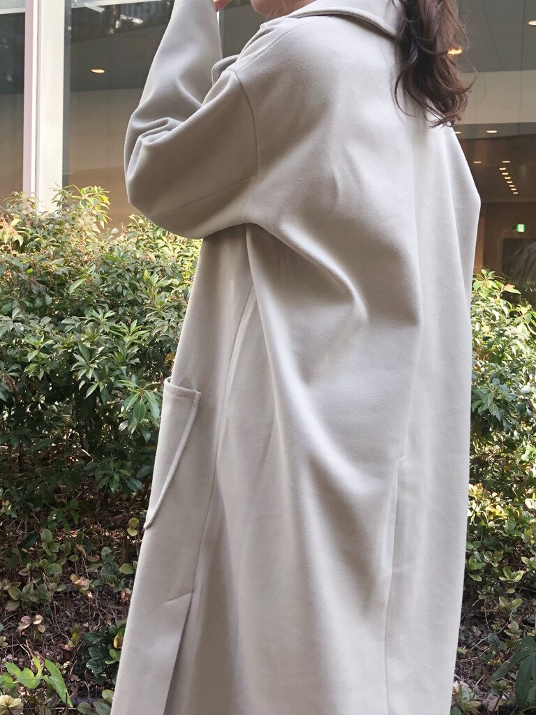 ブラウン系のハンドバッグ、グリーン系のチェスターコート、ホワイト系のブーツを着用したレディースの冬コーディネートの4枚目の写真