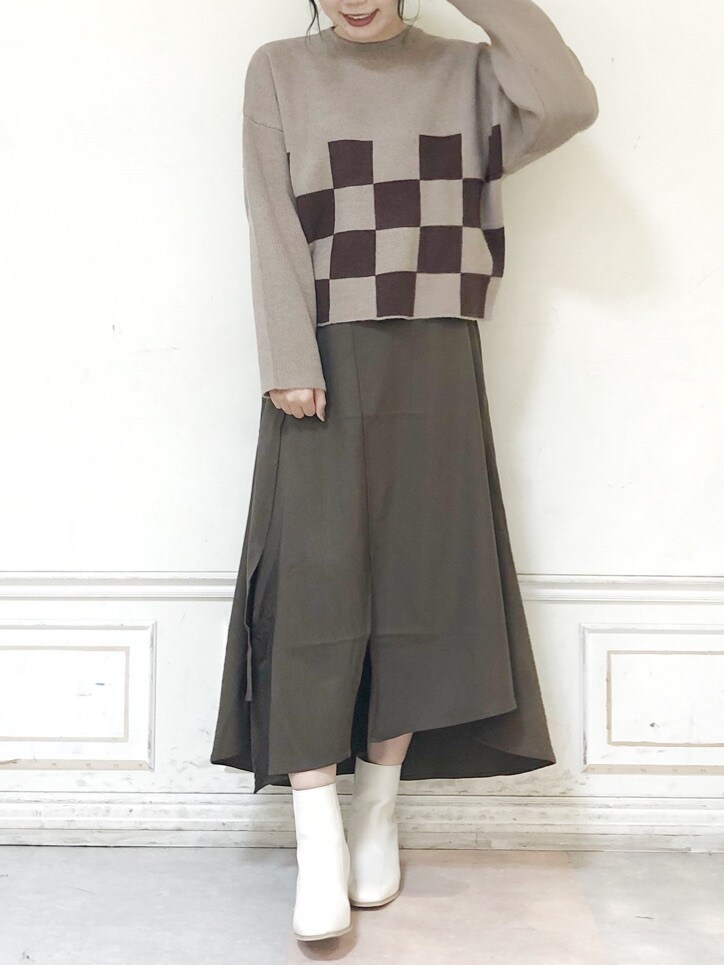 ホワイト系のブーツ、ブラウン系のスカート、ベージュ系のニット/セーターを着用したレディースの秋コーディネートの2枚目の写真
