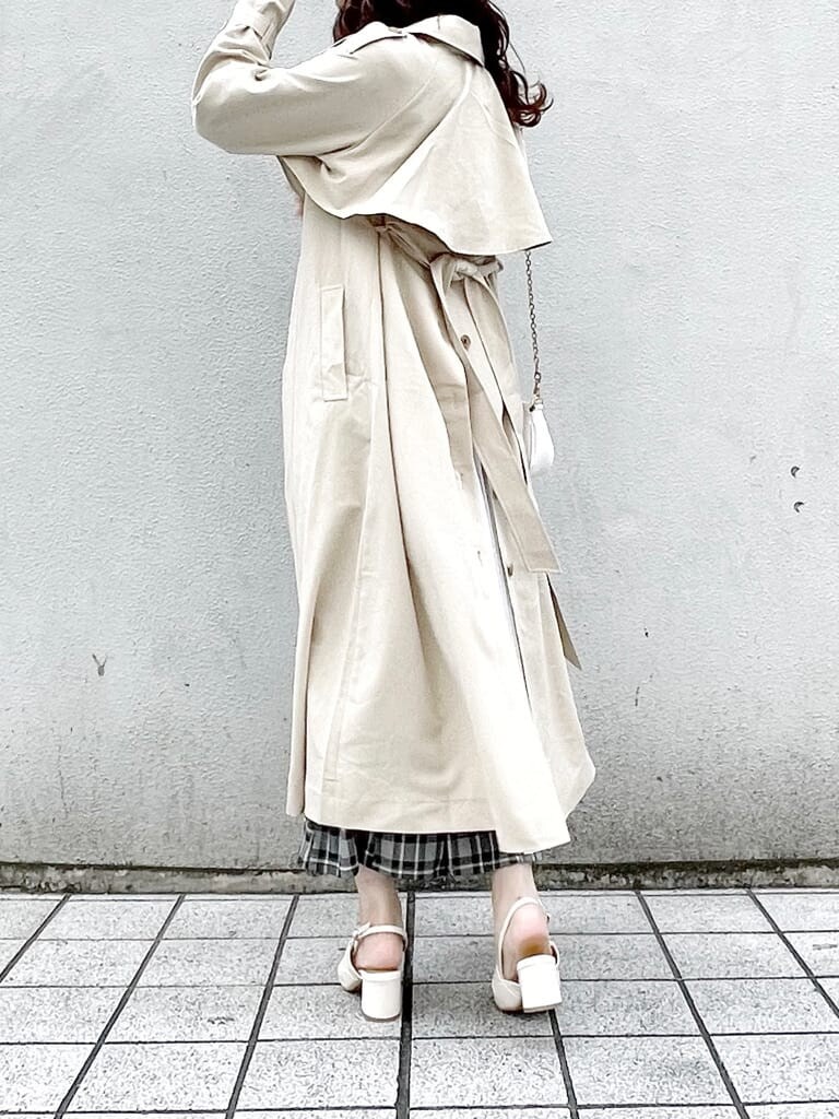 ベージュ系のトレンチコート、ブラック系のスカート、グリーン系のニット/セーターを着用したレディースの冬コーディネートの2枚目の写真