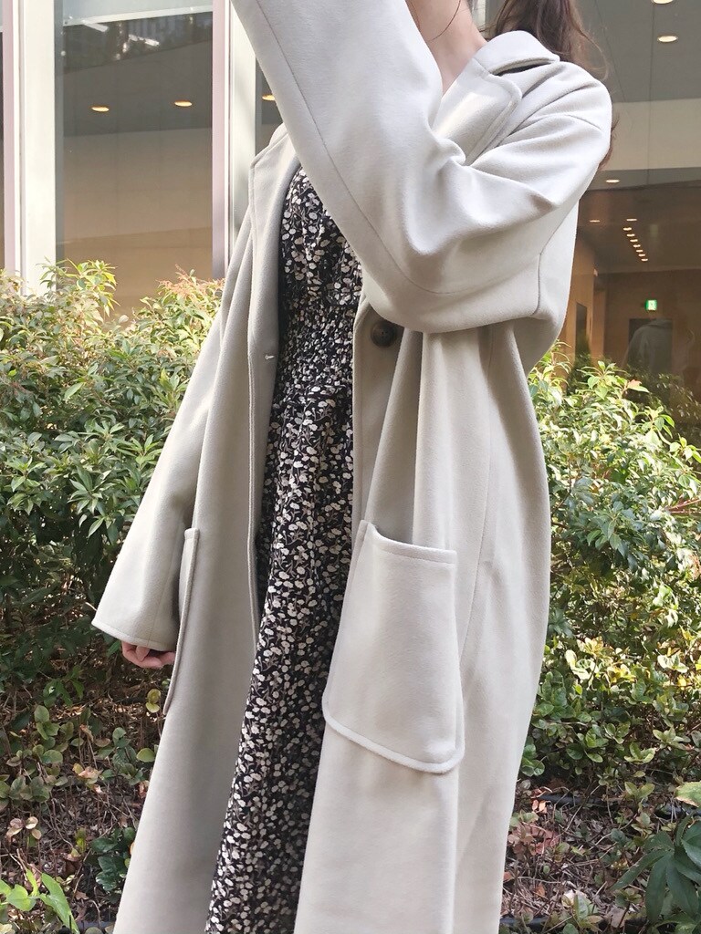 ブラウン系のハンドバッグ、グリーン系のチェスターコート、ホワイト系のブーツを着用したレディースの冬コーディネートの5枚目の写真