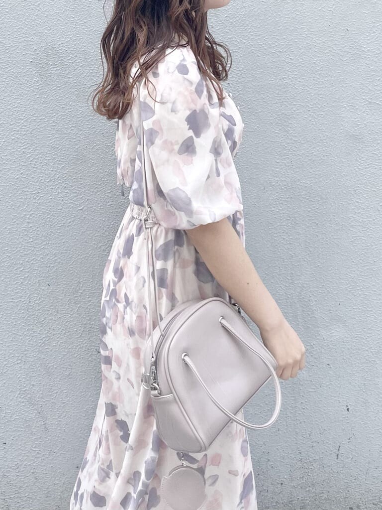 ピンク系のワンピース、ホワイト系のパンプス、ベージュ系のハンドバッグを着用したレディースの春コーディネートの5枚目の写真