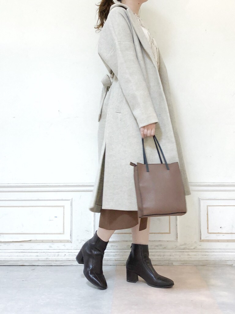 ブラウン系のハンドバッグ、ブラウン系のブーツ、ブラウン系のスカートを着用したレディースの秋コーディネートの3枚目の写真