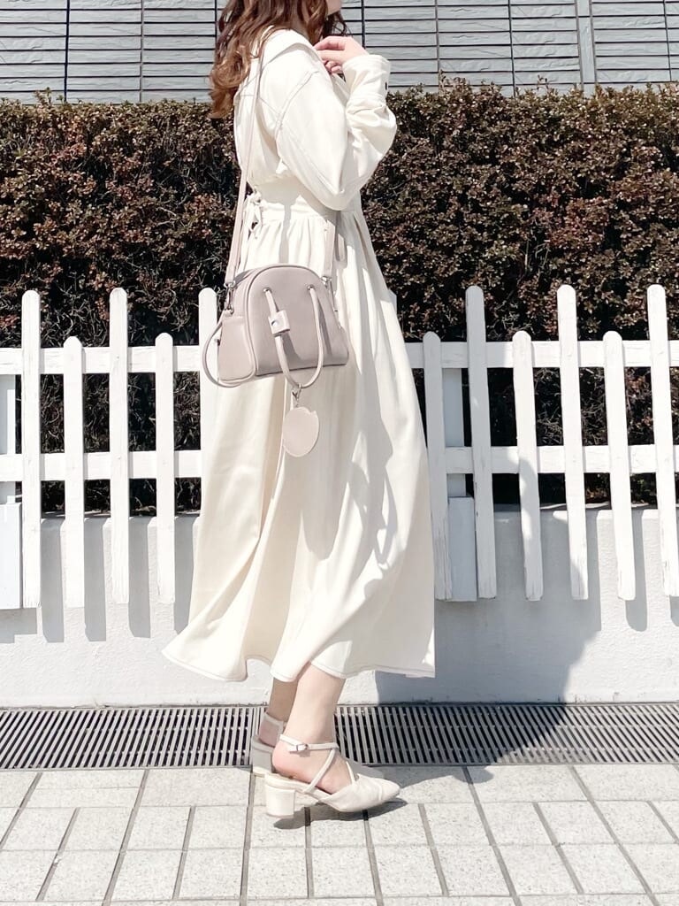 ホワイト系のワンピース、ホワイト系のパンプス、ベージュ系のハンドバッグを着用したレディースの春コーディネートの2枚目の写真