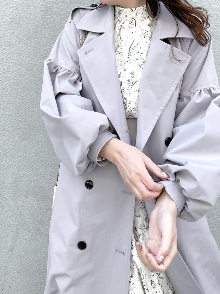 グレー系のトレンチコート、ホワイト系のワンピース、ホワイト系のパンプスを着用したレディースの冬コーディネートの3枚目の写真