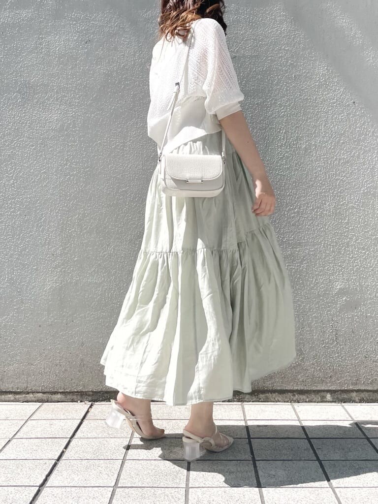 パープル系のサンダル、ホワイト系のショルダーバッグ、グリーン系のワンピースを着用したレディースの春コーディネートの2枚目の写真