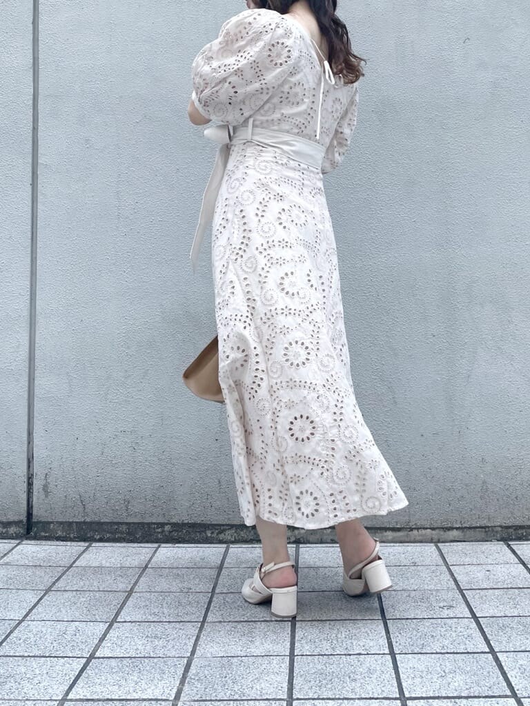 ホワイト系のワンピース、ベージュ系のハンドバッグ、ホワイト系のパンプスを着用したレディースの春コーディネートの2枚目の写真