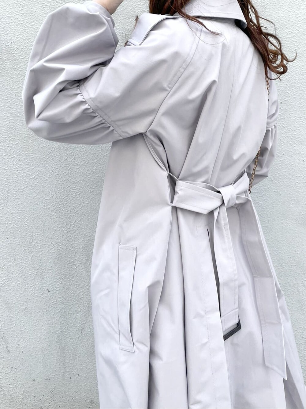 グレー系のトレンチコート、ホワイト系のワンピース、ホワイト系のパンプスを着用したレディースの冬コーディネートの5枚目の写真