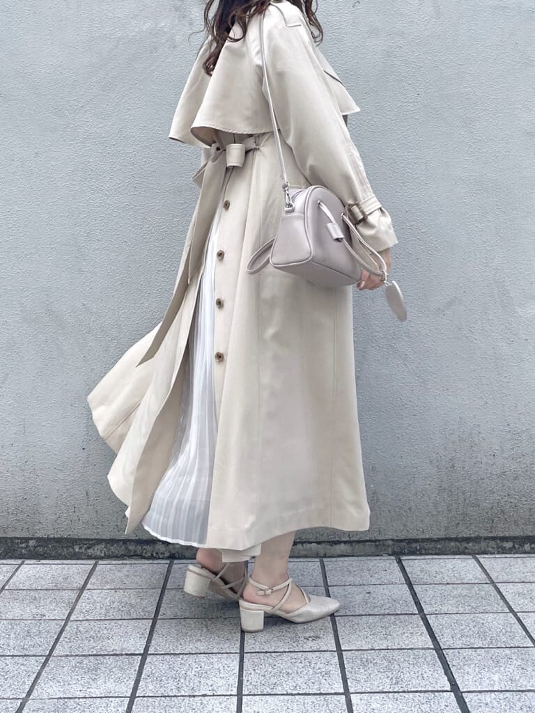 ベージュ系のトレンチコート、ピンク系のワンピース、ホワイト系のパンプスを着用したレディースの春コーディネートの3枚目の写真