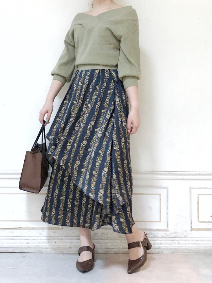 ブラック系のスカート、ブラウン系のハンドバッグ、グリーン系のニット/セーターを着用したレディースの秋コーディネートの2枚目の写真