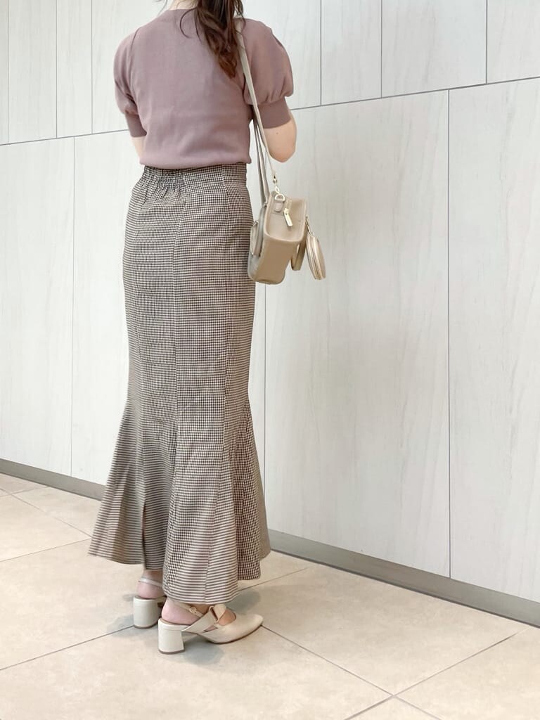 ブラウン系のスカート、ピンク系のニット/セーター、ベージュ系のハンドバッグを着用したレディースの秋コーディネートの2枚目の写真