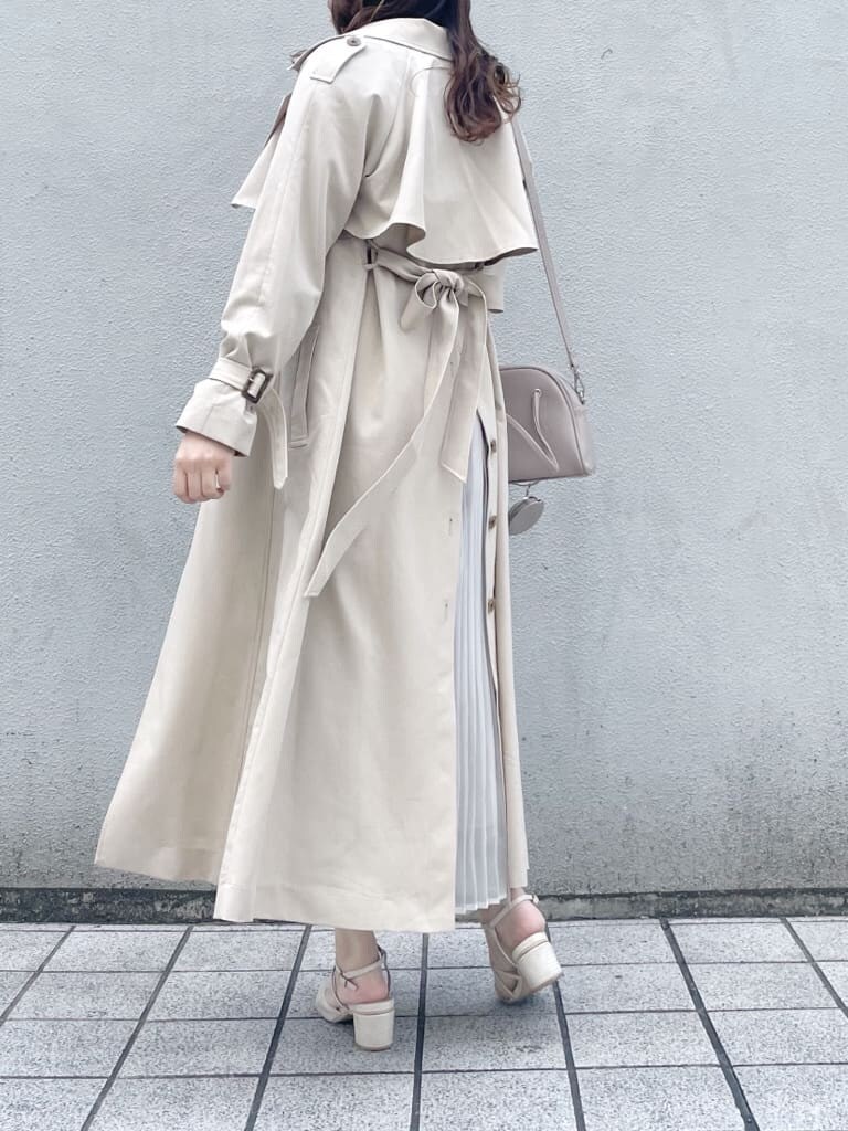 ベージュ系のトレンチコート、ピンク系のワンピース、ホワイト系のパンプスを着用したレディースの春コーディネートの2枚目の写真
