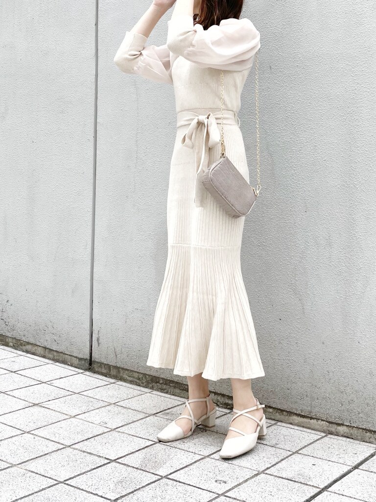 ベージュ系のワンピース、ホワイト系のパンプス、ベージュ系のショルダーバッグを着用したレディースの冬コーディネートの3枚目の写真