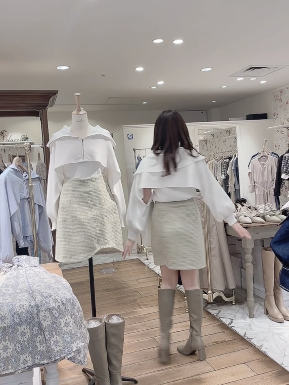 グリーン系のスカート、ベージュ系のブーツ、ホワイト系のニット/セーターを着用したレディースの冬コーディネートの2枚目の写真