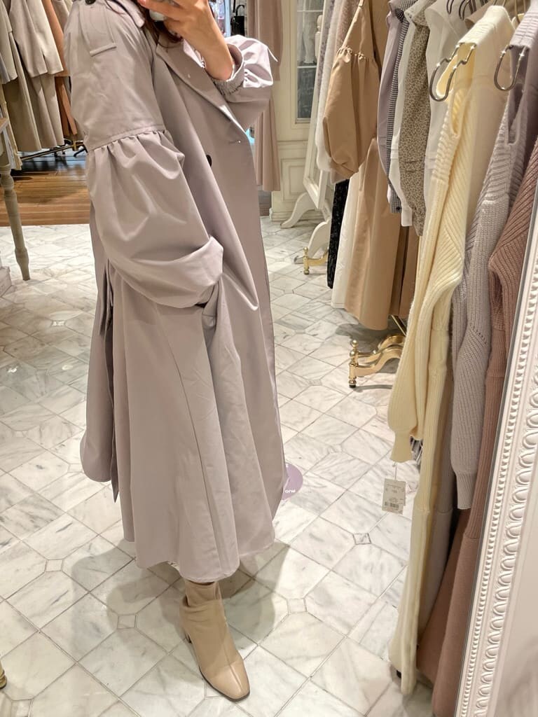 ベージュ系のブーツ、グレー系のトレンチコート、ホワイト系のワンピースを着用したレディースの冬コーディネートの3枚目の写真