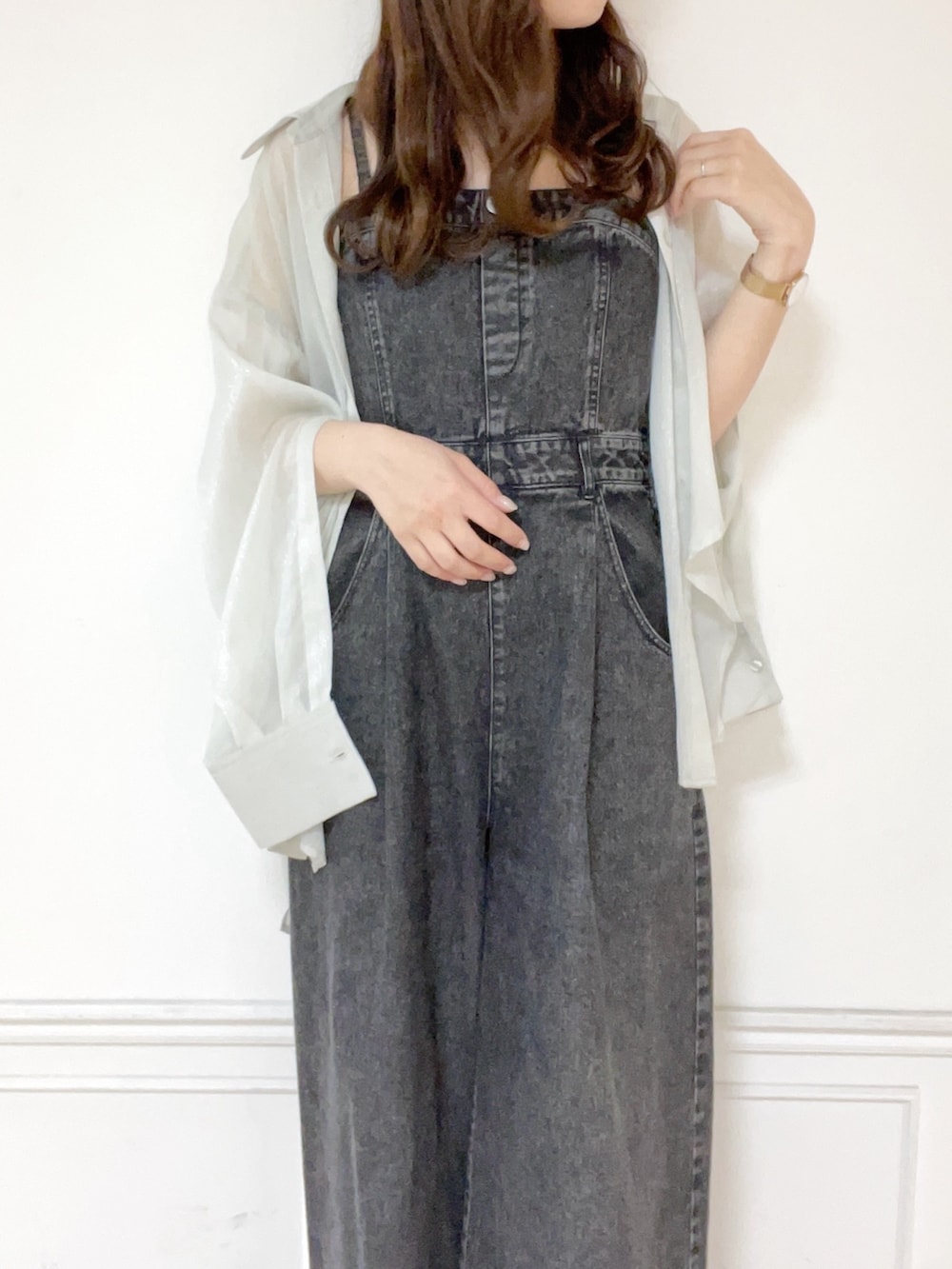 ブラック系のサロペット/オーバーオール、グリーン系のシャツ/ブラウス、ホワイト系のパンプスを着用したレディースの春コーディネートの2枚目の写真