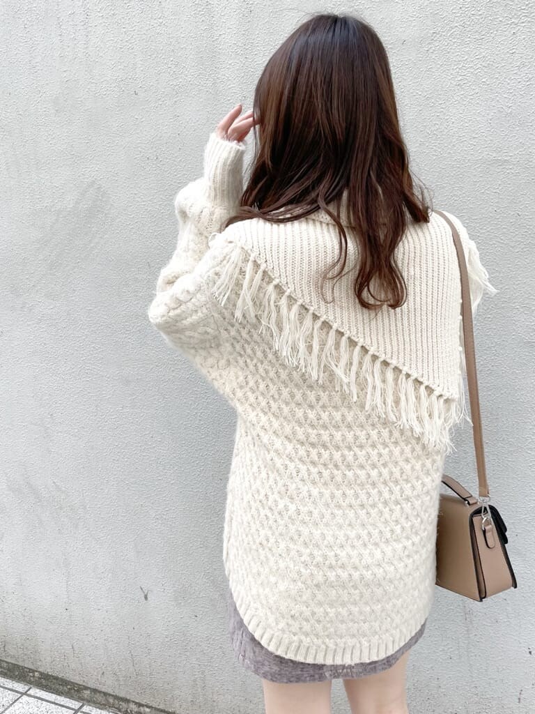 グレー系のスカート、ベージュ系のブーツ、ベージュ系のハンドバッグを着用したレディースの秋コーディネートの4枚目の写真