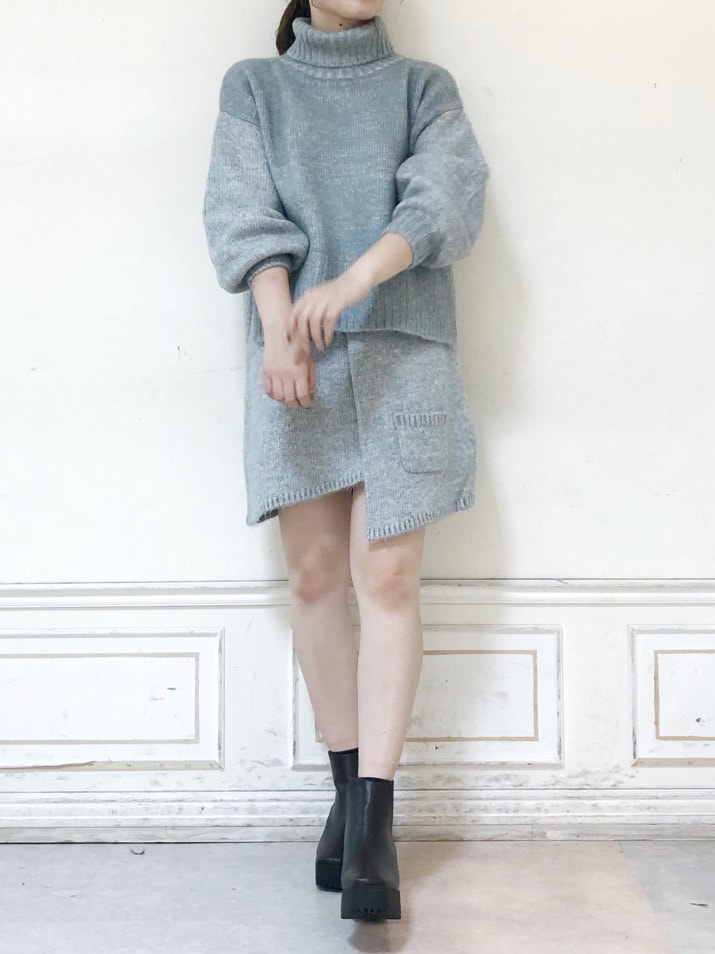グレー系のスカート、グレー系のニット/セーター、ブラウン系のブーツを着用したレディースの秋コーディネートの2枚目の写真