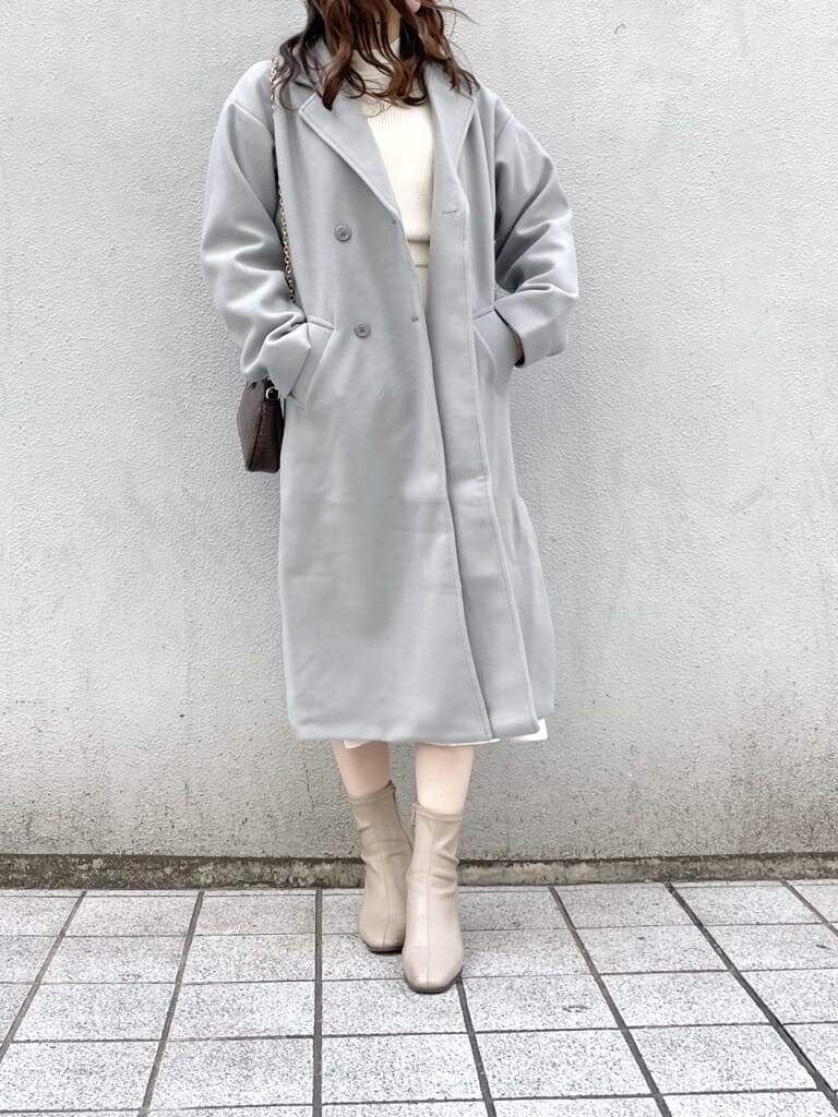 ベージュ系のブーツ、ホワイト系のワンピース、ブルー系のチェスターコートを着用したレディースの冬コーディネートの3枚目の写真