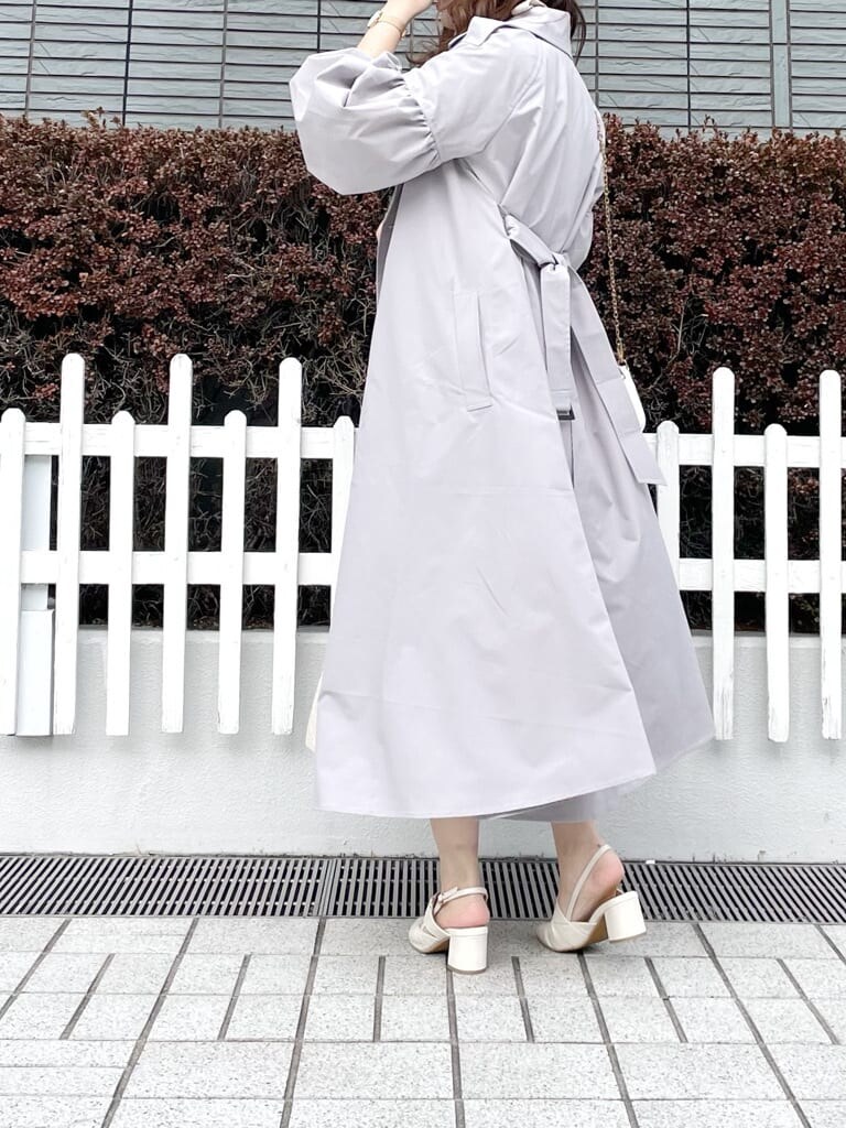 グレー系のトレンチコート、ホワイト系のワンピース、ホワイト系のパンプスを着用したレディースの春コーディネートの2枚目の写真