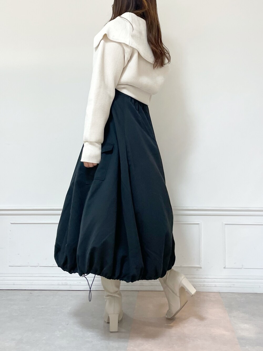 ホワイト系のニット/セーター、ブラック系のスカート、ホワイト系のブーツを着用したレディースの秋コーディネートの3枚目の写真