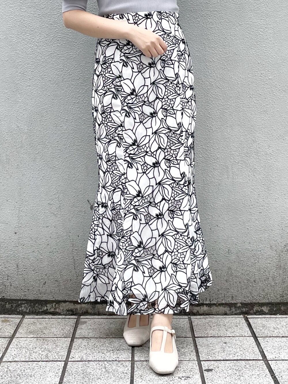 ブルー系のニット/セーター、ホワイト系のスカート、ホワイト系のパンプスを着用したレディースの春コーディネートの4枚目の写真