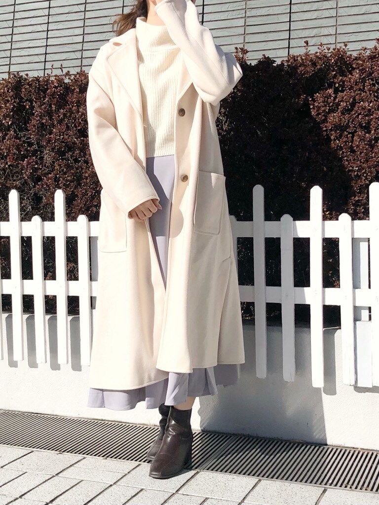 ホワイト系のチェスターコート、ブラウン系のブーツ、グレー系のスカートを着用したレディースの冬コーディネートの2枚目の写真