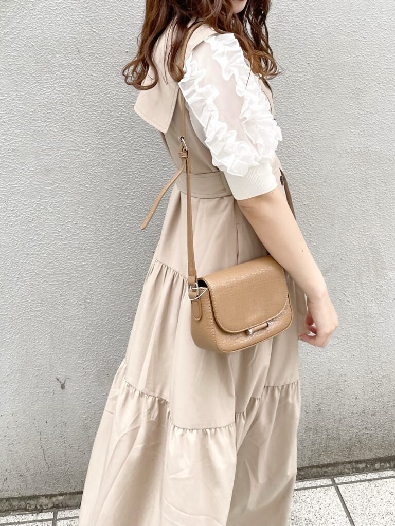 ベージュ系のワンピース、ホワイト系のパンプス、ブラウン系のショルダーバッグを着用したレディースの春コーディネートの6枚目の写真