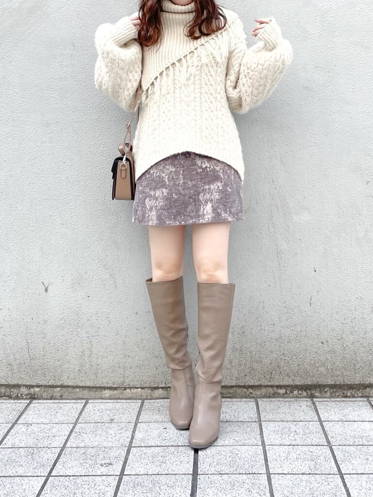 グレー系のスカート、ベージュ系のブーツ、ベージュ系のハンドバッグを着用したレディースの秋コーディネートの2枚目の写真