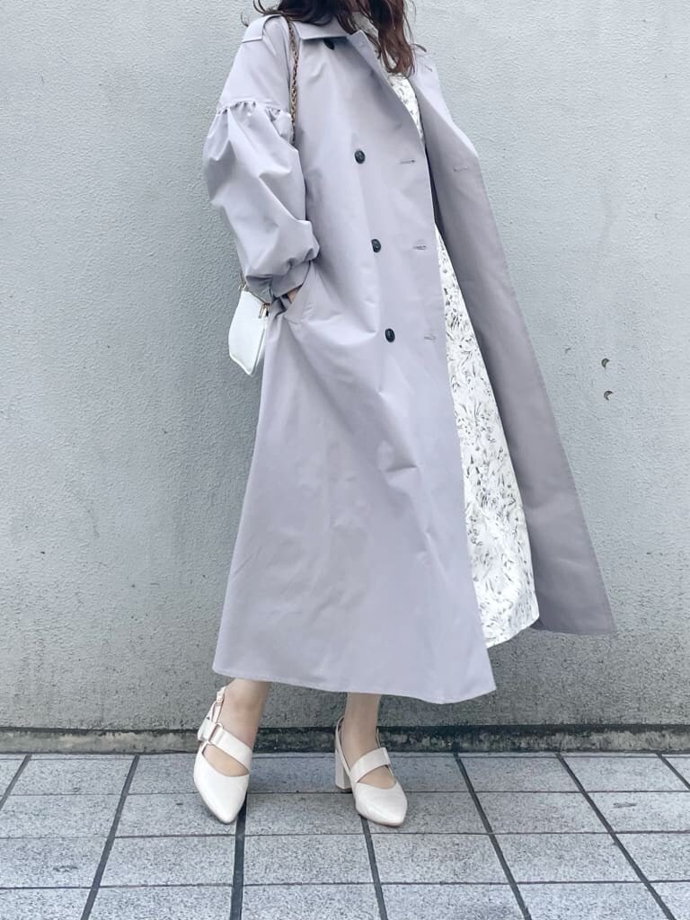 グレー系のトレンチコート、ホワイト系のワンピース、ホワイト系のパンプスを着用したレディースの冬コーディネートの2枚目の写真