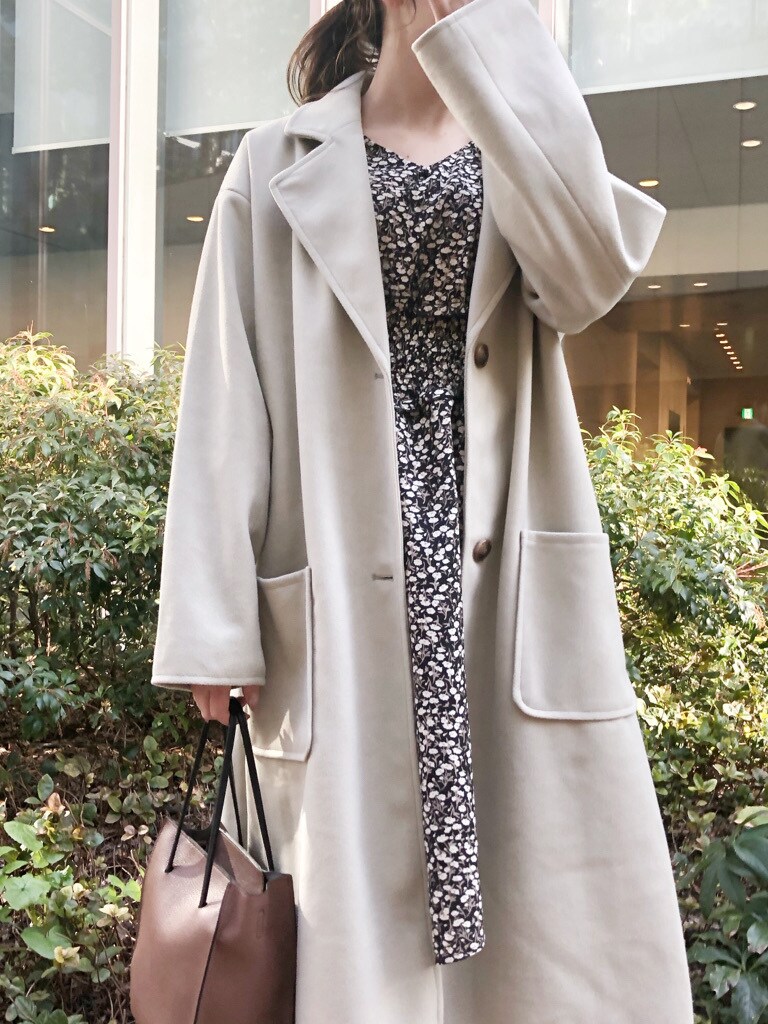 ブラウン系のハンドバッグ、グリーン系のチェスターコート、ホワイト系のブーツを着用したレディースの冬コーディネートの2枚目の写真