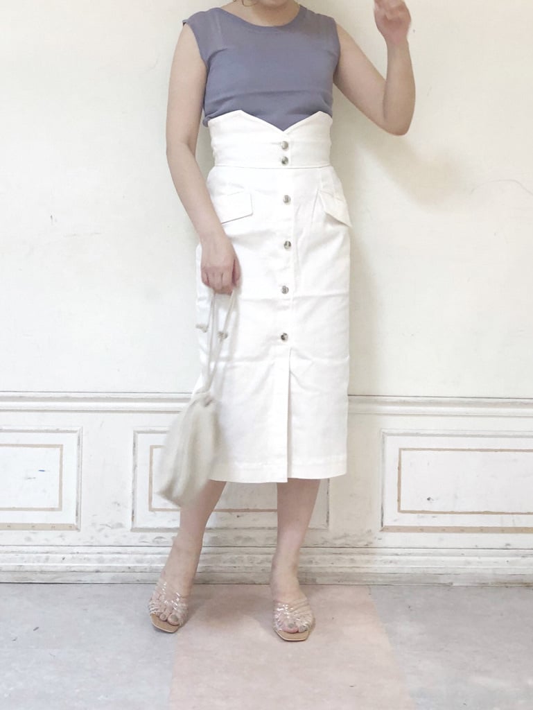 ホワイト系のデニムスカート、ホワイト系のハンドバッグ、パープル系のニット/セーターを着用したレディースの夏コーディネートの3枚目の写真