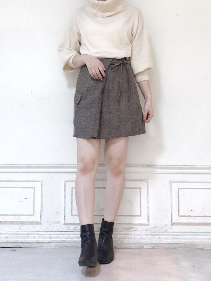 ブラウン系のスカート、ブラウン系のブーツ、ホワイト系のニット/セーターを着用したレディースの秋コーディネートの2枚目の写真